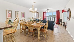 A dining area with a wooden table and chairs, a chandelier, and a view of the outdoors.