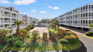 Een modern hotel met meerdere verdiepingen, balkons en een centrale binnenplaats met tropisch groen.