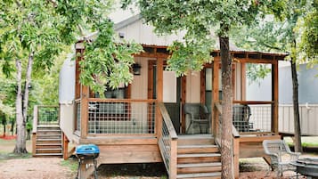Eine Holzterrasse mit einem Stuhl, einem Grill und einer überdachten Sitzgelegenheit.