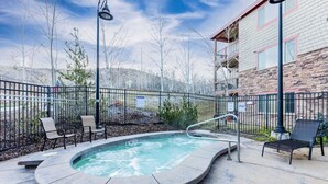 Un jacuzzi rodeado de sillas y una valla, con un edificio al fondo.