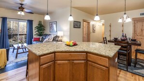 Una cocina con encimeras de granito, armarios de madera e iluminación colgante.