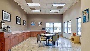 A spacious kitchen area with a long counter, multiple chairs, and a large window providing natural light. - Studio 6 Effingham, Il (Effingham)