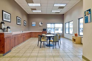 A spacious kitchen area with a long counter, multiple chairs, and a large window providing natural light.