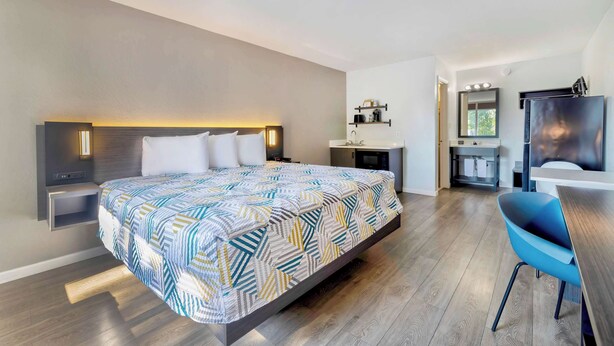 A modern hotel room with a large bed, bedside tables, a desk, and a chair. - Studio 6 Effingham, Il (Effingham)