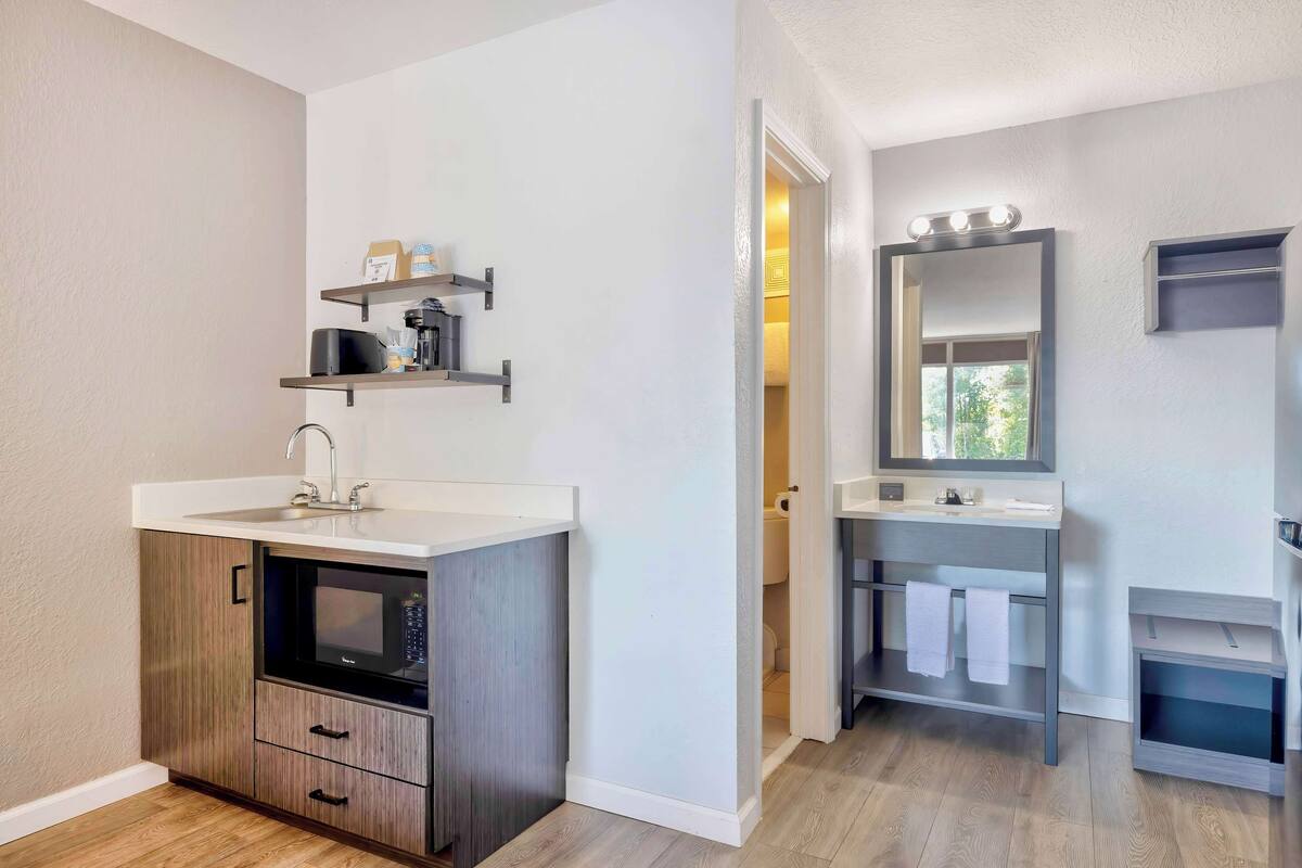 A compact bathroom with a sink, mirror, and shelves.