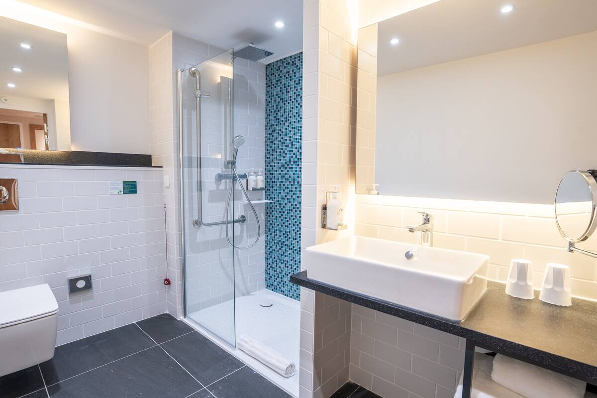 A modern bathroom with a glass-enclosed shower, a white sink, and a mirror.