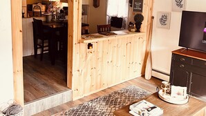 Un salon chaleureux avec un plancher en bois, une table basse, un téléviseur et une cheminée.