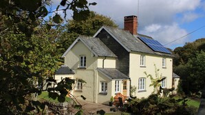 Ein zweistöckiges Haus mit Schornstein, Solaranlage und Garten.