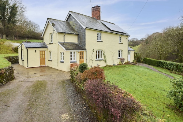 A two-story house with a paved driveway and a well-maintained lawn.