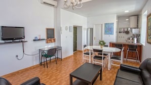 Una sala de estar moderna con televisor, comedor y cocina.