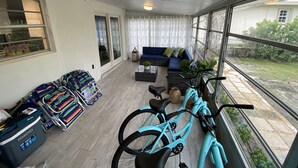 Une pièce baignée de lumière, avec un canapé bleu, un vélo et un chariot rempli de bagages.