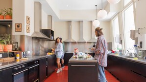 A modern kitchen with stainless steel appliances, a central island, and a red floor. - Bounce Melbourne (Melbourne)