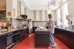 Una cocina moderna con electrodomésticos de acero inoxidable, una isla central y piso rojo.