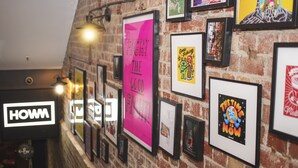 A wall with various framed artworks and a sign that reads "HOWM". - Bounce Melbourne (Melbourne)