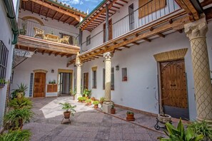 A courtyard with a wooden pergola, potted plants, and a wooden door.