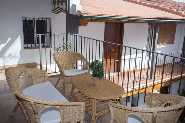 A balcony with wicker furniture and a potted plant.