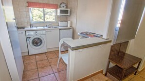A compact kitchen with a washing machine, a microwave, and a small dining area. - Private penthouse with terrace in the historic center (Jerez de la Frontera)