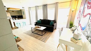 A modern living room with a sofa, coffee table, and a dining area with a table and chairs. - The Beach Bungalow - In the Heart of Destin, FL!   (Destin)