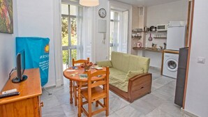 Kompakti oleskelutila, jossa on ruokailualue, sohva, pesukone ja keittiö.