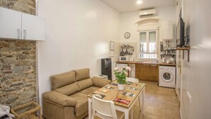 Un espacio habitable pequeño con sofá, mesa de comedor y kitchenette.