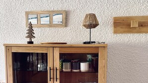 Um armário de madeira com portas de vidro, gavetas e prateleiras contendo pratos e xícaras.