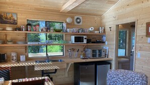 A compact kitchen with wooden walls, a sink, a microwave, and a refrigerator. - Ocean Front wilderness Cabin, brand new - Spa bathroom, fully equipped Kitchen (Quatsino)
