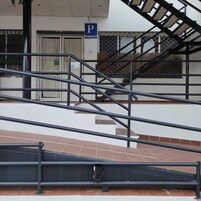 Una escalera que lleva a un nivel superior, con un letrero de estacionamiento azul y un letrero que dice 'VISA' en la puerta.