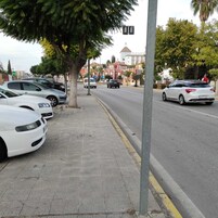 Una calle con autos estacionados y aceras.