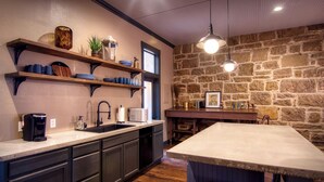 Una cocina con estantes de madera, pared de piedra y una isla grande.