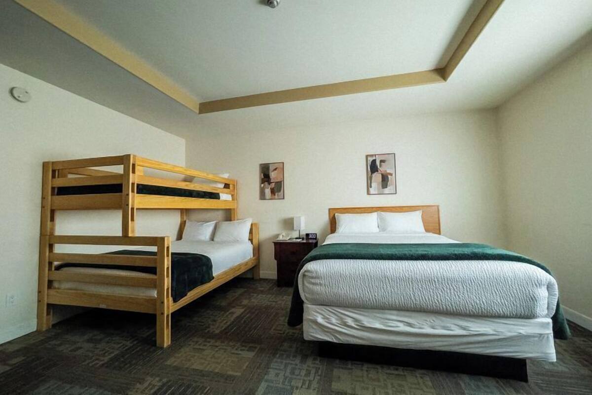 A room with a bunk bed, a single bed, a nightstand, and two wall-mounted pictures.