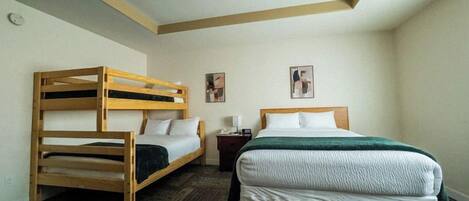 A room with a bunk bed, a single bed, a nightstand, and two wall-mounted pictures.
