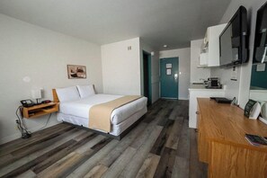 Ein Hotelzimmer mit Bett, Nachttisch, Schreibtisch und Fernseher.