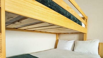 A bunk bed with a wooden frame, a white mattress, and a green blanket.