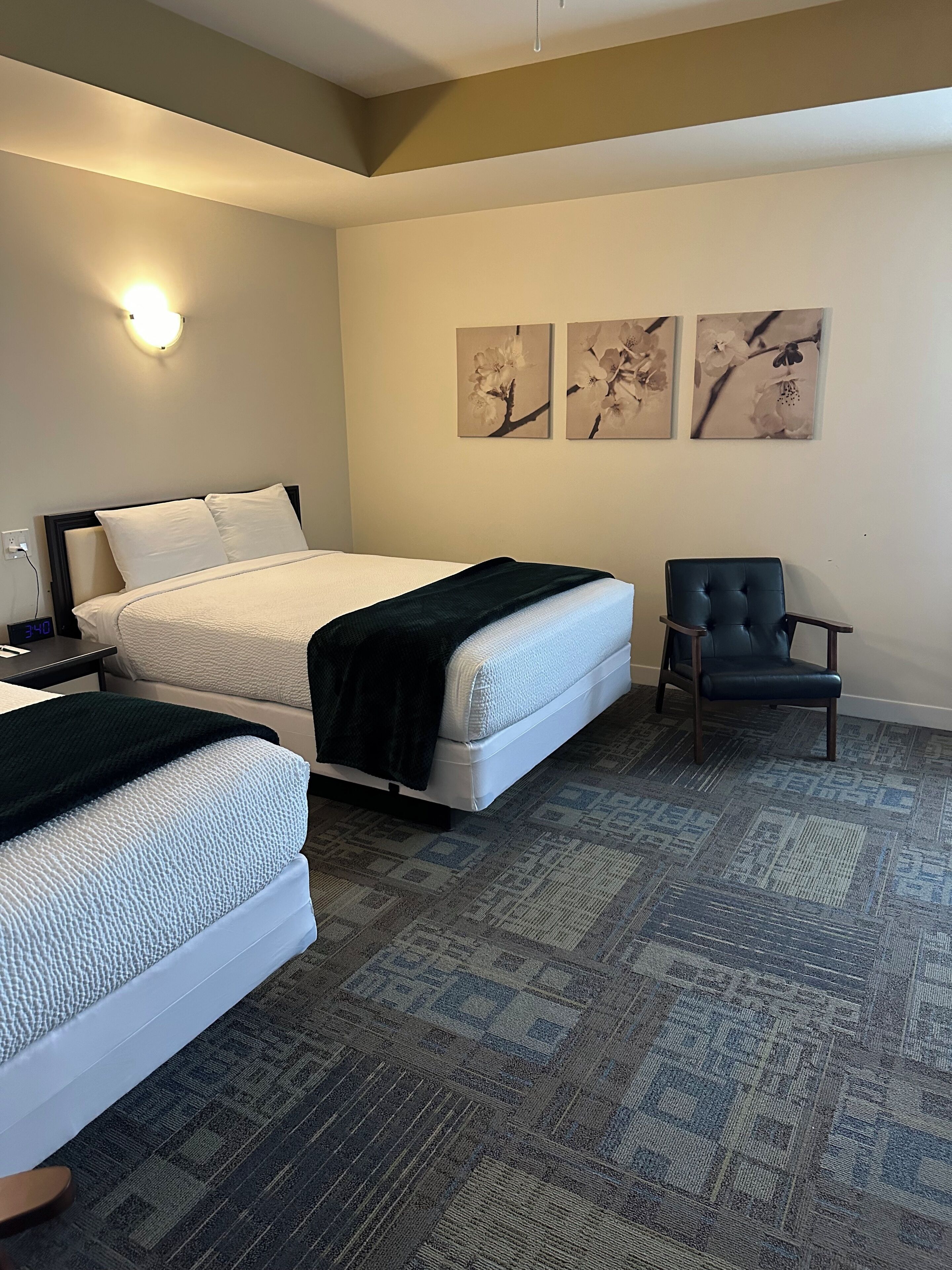 Ein Hotelzimmer mit zwei Betten, einem Sessel und Wandbildern.