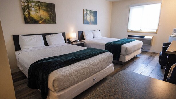 A hotel room with two beds, a desk, and a window. - Sleep Suite Motel (Steinbach)
