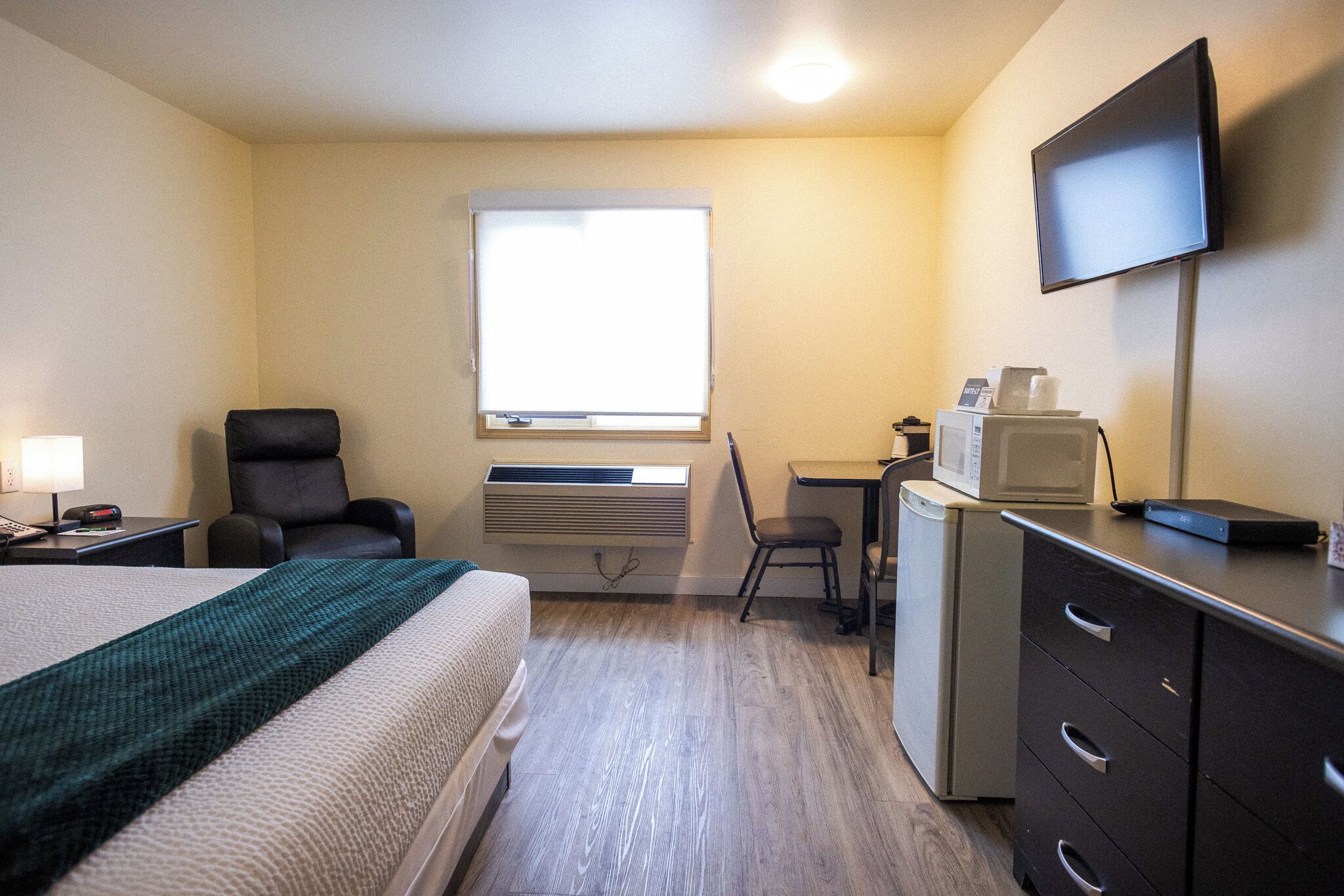 Ein Hotelzimmer mit Bett, Schreibtisch, Stuhl, Fernseher und einer Mikrowelle.