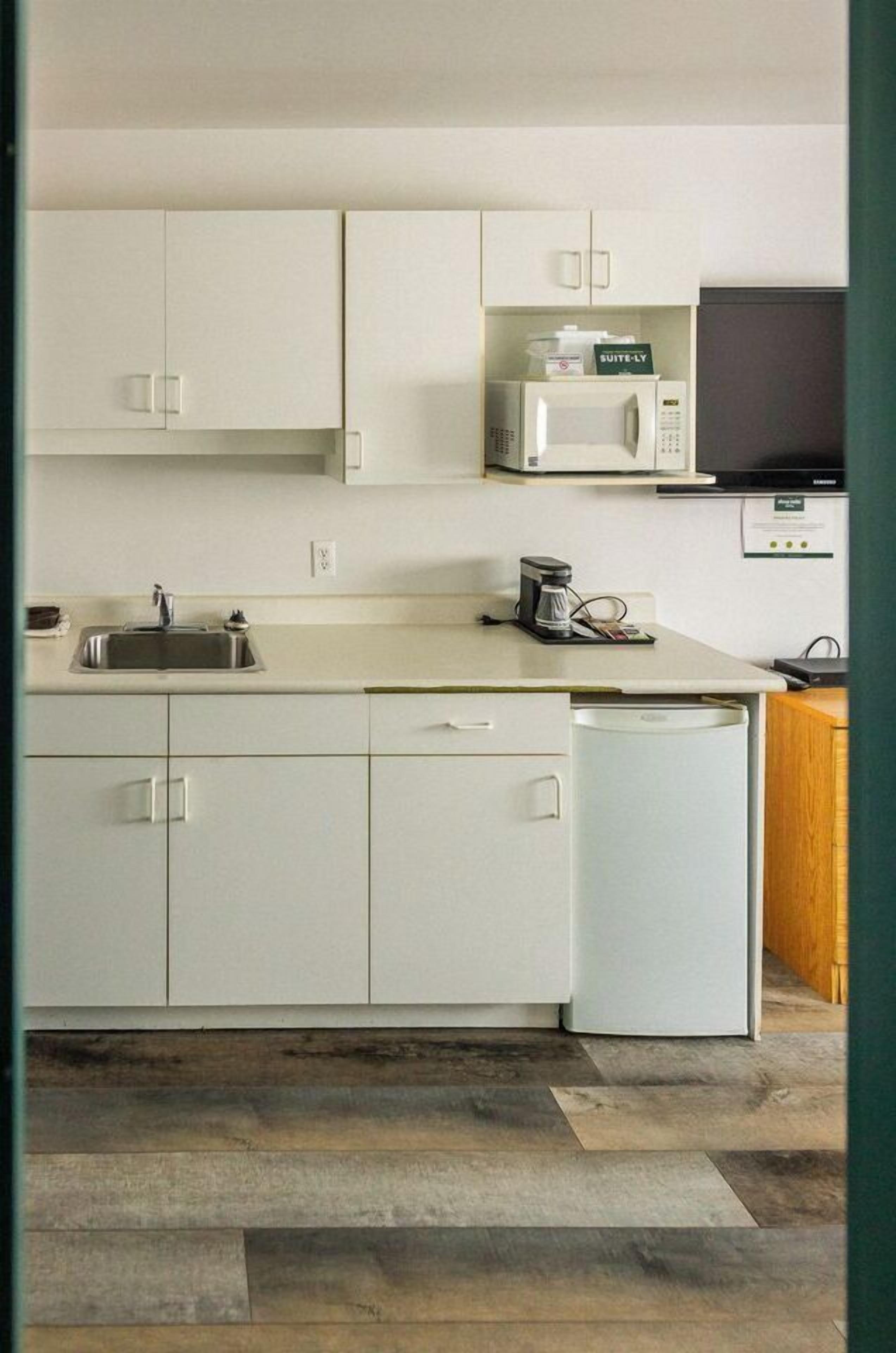 A modern kitchen with white cabinets, a microwave, a coffee maker, and a dishwasher.