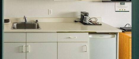 A modern kitchen with white cabinets, a microwave, a coffee maker, and a dishwasher.
