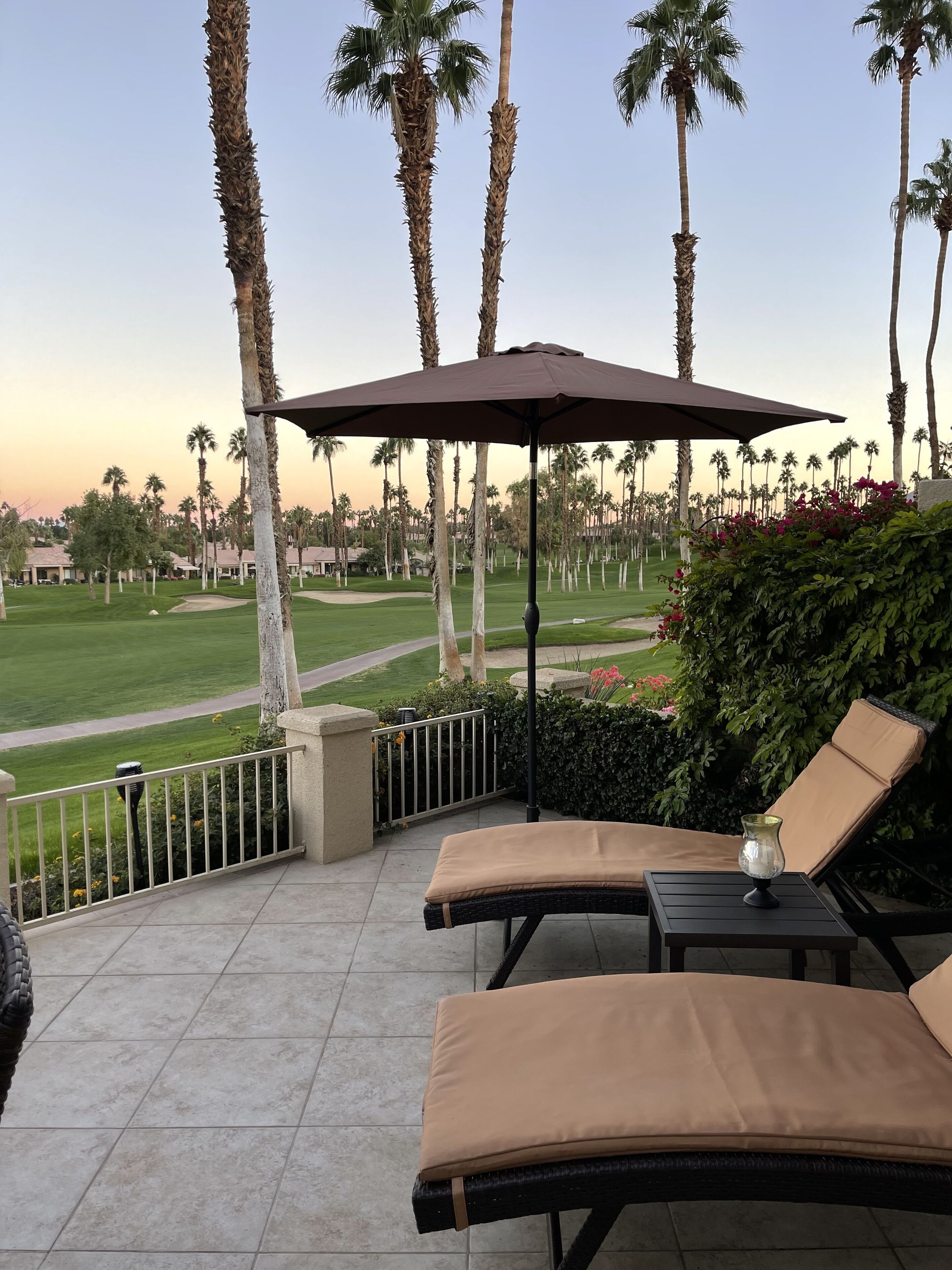 A patio with two lounge chairs, a table, and a large umbrella.