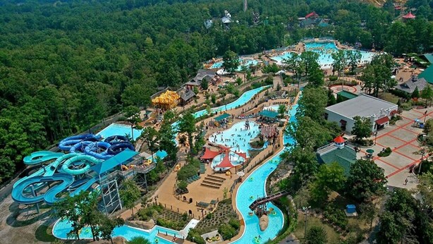 Vista aérea de un parque acuático con múltiples piscinas, toboganes de agua y un edificio grande.