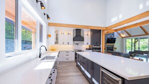 Una cocina moderna con armarios blancos, una isla grande y una chimenea de piedra.