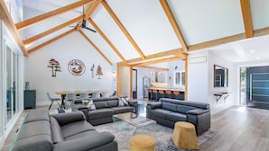 Amplia sala de estar con muebles modernos, comedor y cocina al fondo.