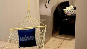 Una habitación con una silla hamaca, un cartel de bienvenida y una butaca con almohada.