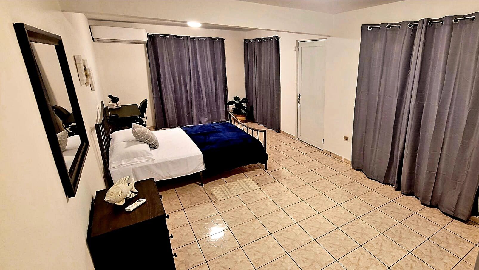 Une chambre d’hôtel comprenant un lit, un bureau avec une chaise, une petite table et un miroir.