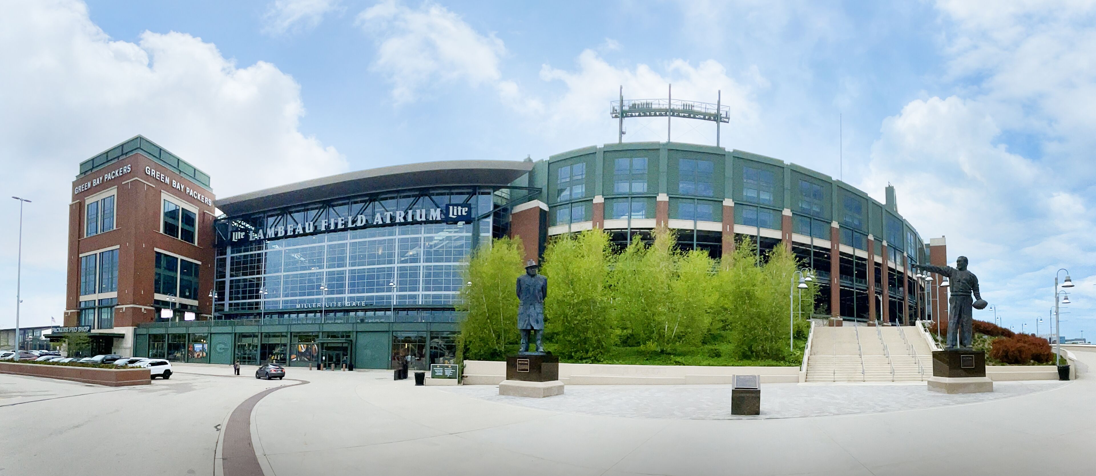 A stadium with a large glass facade, a statue, and a sign for the Green Bay Packers.