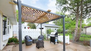 A covered patio area with outdoor furniture, a grill, and a pergola structure. - Beautiful newly remodeled house .5 miles to Lambeau/Resch center. (Pet Friendly) (Green Bay)
