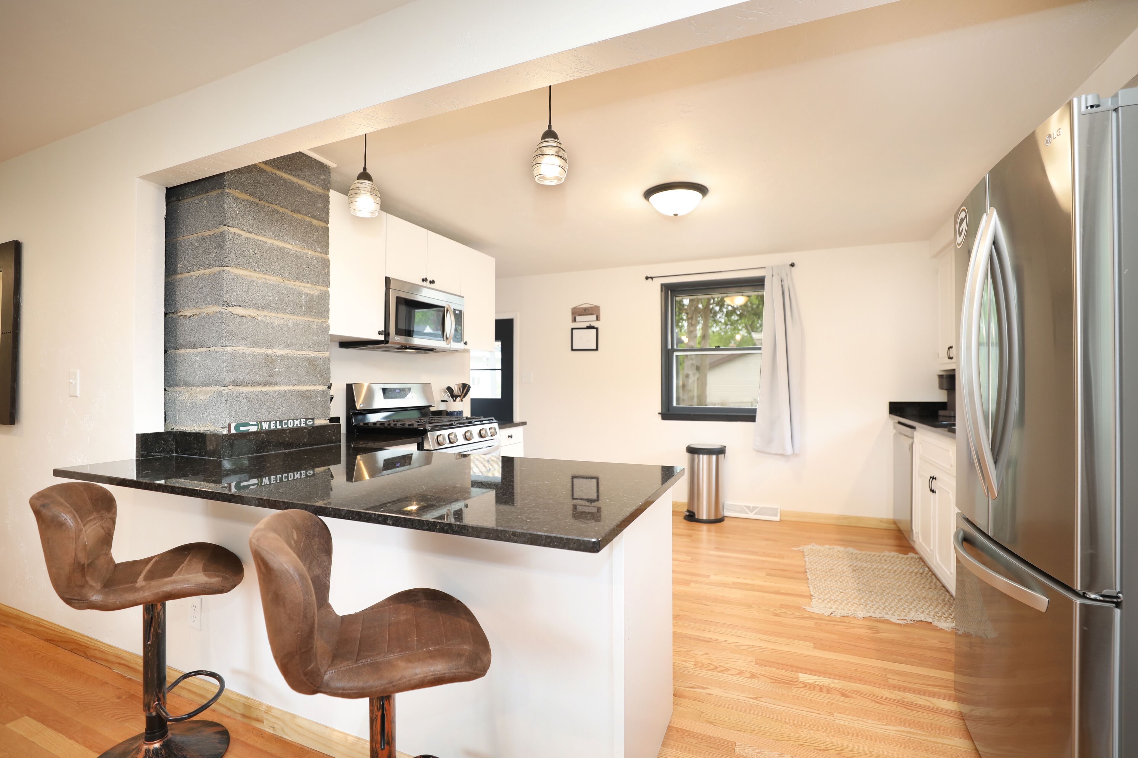 A modern kitchen with a central island, bar stools, stainless steel appliances, and a large refrigerator.