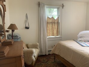 Classic bedroom with a wooden bed, patterned rug, and sheer curtains.