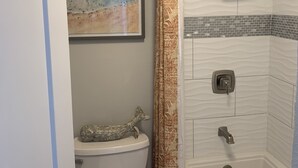 Ein Badezimmer mit Toilette, Dusche und Regendusche sowie einem gemusterten Duschvorhang.