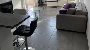 A modern living space with a dining area, a sofa, and a kitchen. - Cosy apartment rental (SANTA LUCIA DI MORIANI)